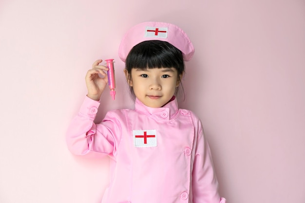 Asian kid playing a nurse isolated on pink