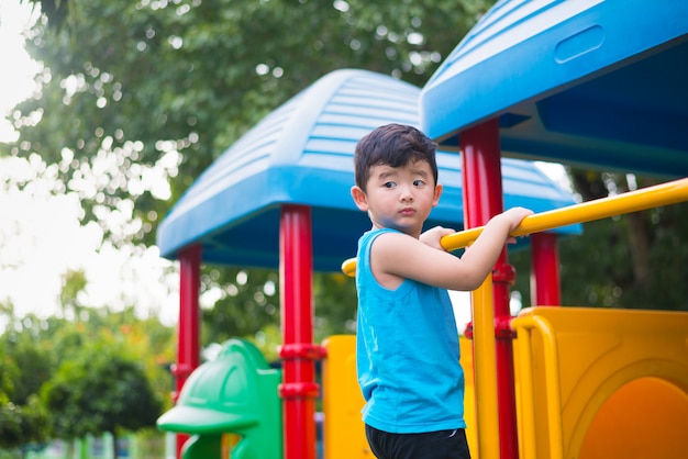 Asian kid playing at the playground under the sunlight in summer