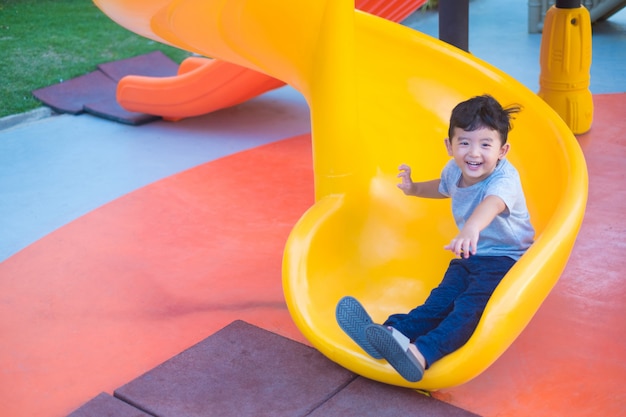 Asian kid playing slide at the playground