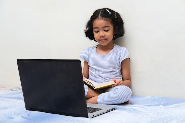 Asian kid reading a book when study in her bed