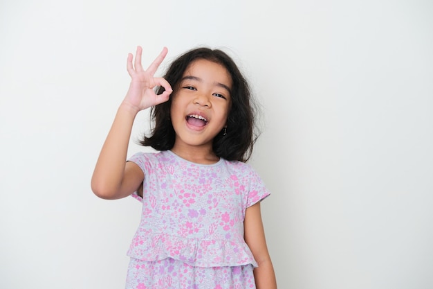 Asian kid smiling while giving OK finger sign