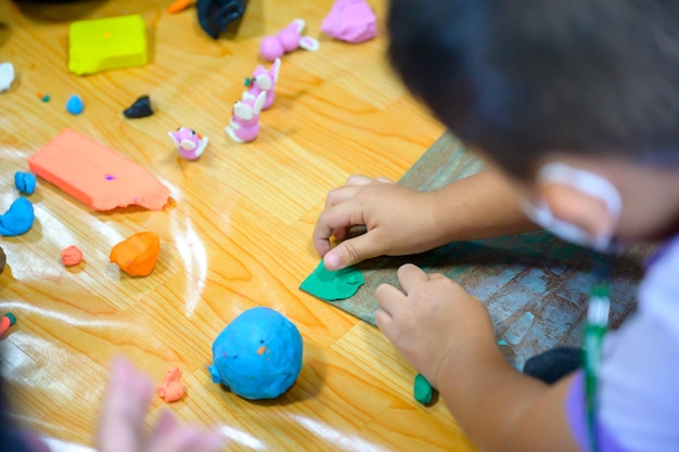 Asian kindergarten students in the classroom at school Sculpting plasticine in the basic art class Children have the skills to sculpt clay and are happy to learn and Basic Art Studies