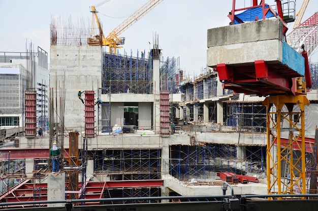 Asian labor people and thai labour workers use machine and heavy machinery working builder new building tower at construction site highrise building on scaffold at capital city in Bangkok Thailand