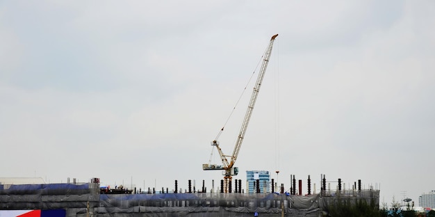 Asian labor people and thai labour workers use machine and heavy machinery working builder new structure tower highrise building on scaffold at construction site at capital city in Bangkok Thailand