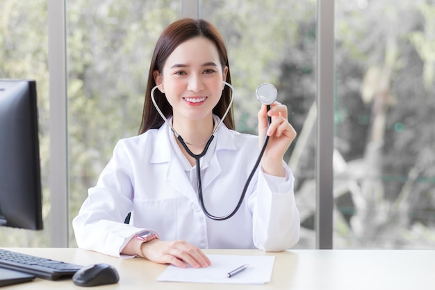 Asian lady doctor wears medical coat and stethoscope and shows its in office room at hospital.