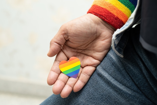 Asian lady holding rainbow color flag heart symbol of LGBT pride month