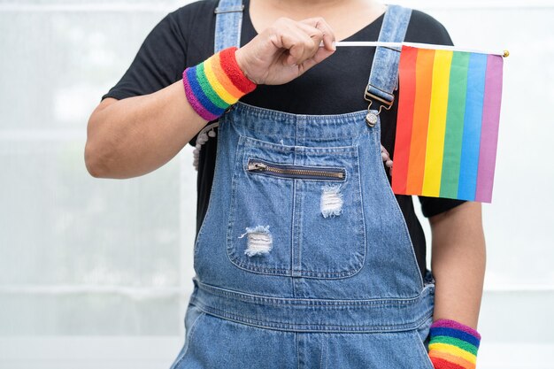 Asian lady holding rainbow color flag symbol of LGBT pride month celebrate annual in June