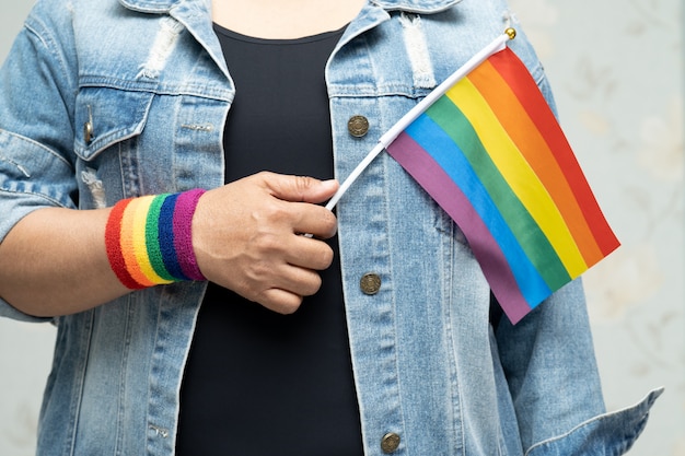 Asian lady holding rainbow color flag, symbol of LGBT pride month.