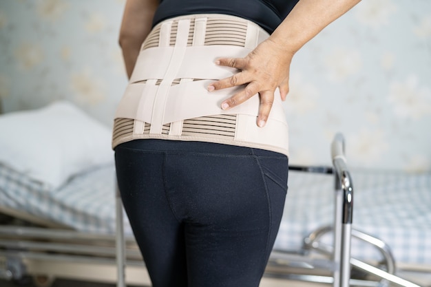 Asian lady patient wearing back pain support belt for orthopedic lumbar with walker.