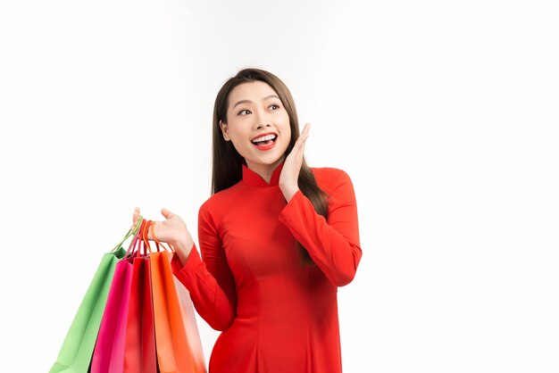 Asian lady in red ao dai dress holding shopping bags isolated on white, Happy lunar new year