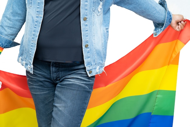 Photo asian lady wearing blue jean jacket or denim shirt and holding rainbow color flag, symbol of lgbt pride month.