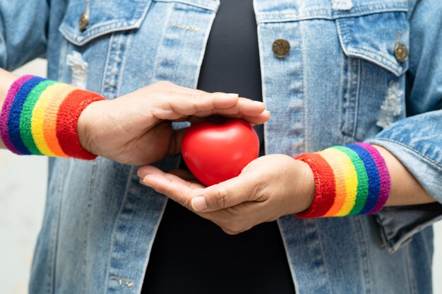 Asian lady wearing rainbow wristbands and hold red heart