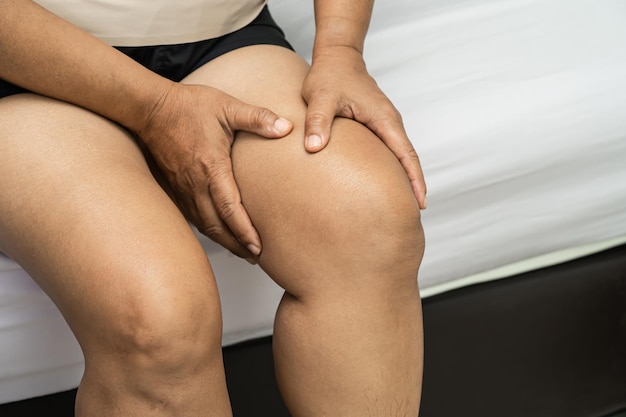 Asian lady woman patient touch and feel pain her knee healthy medical concept