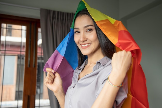 Asian LGBT woman holding LGBTQ rainbow flag lesbian pride or LGBT pride movement inclusivity diversity of people concept