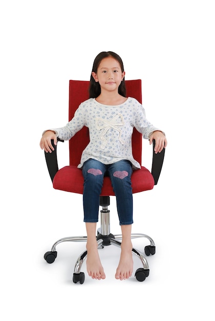 Asian little girl child looking at camera with sitting and relax on chair isolated on white studio background Image full length with Clipping path