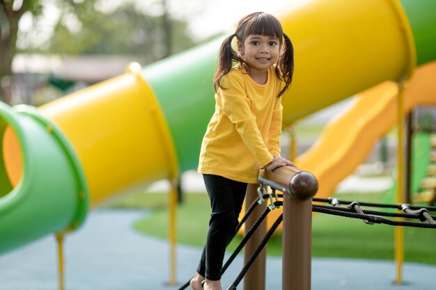 Asian little girl enjoys playing in a children playground Outdoor portrait