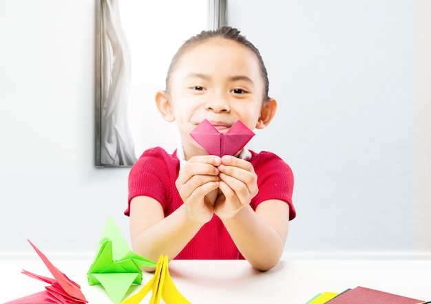 Asian little girl showing her papercraft at home