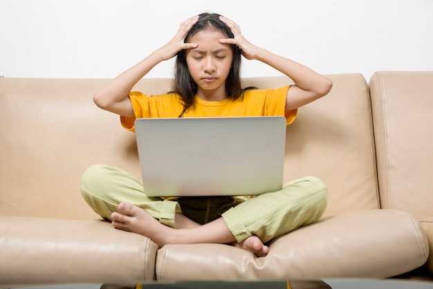 Asian little girl with laptop feeling stress for online school class at home. Online education during quarantine