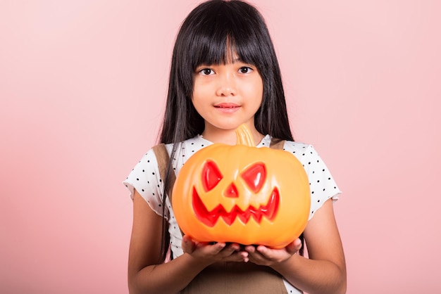 Asian little kid 10 years old holding carved Halloween pumpkin