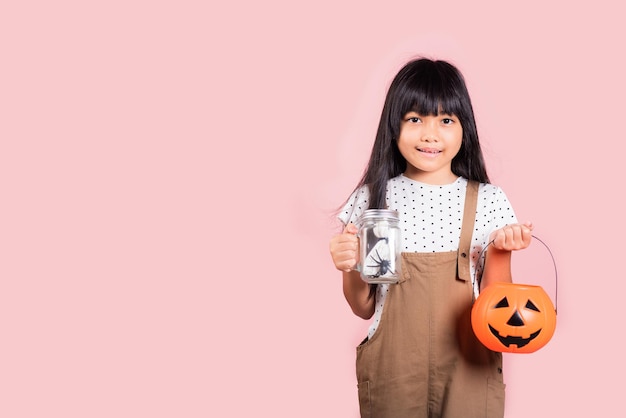 Asian little kid 10 years old holding Jack O pumpkin basket to collect candy trick