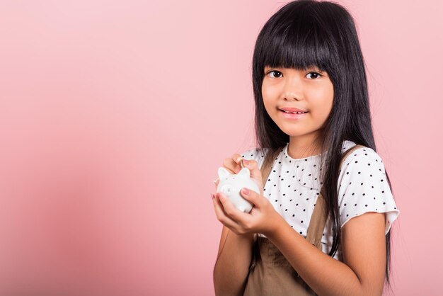 Asian little kid 10 years old holding piggy bank and looking at camera