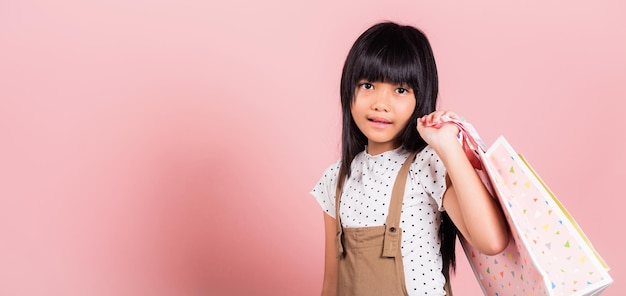 Asian little kid 10 years old smiling holding multicolor shopping bags in hands