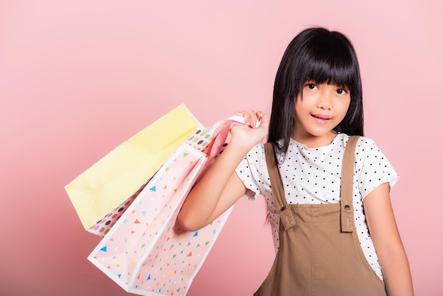 Asian little kid 10 years old smiling holding multicolor shopping bags in hands