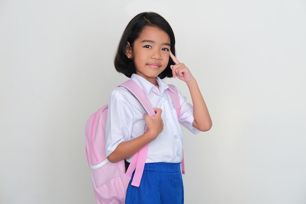 Asian little kid wearing school uniform smiling while pointing to her brain