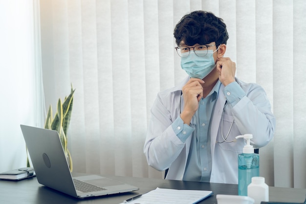 Asian male doctor wearing a mask at his office