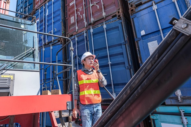 Asian male engineer using radio communication working at the warehouse container