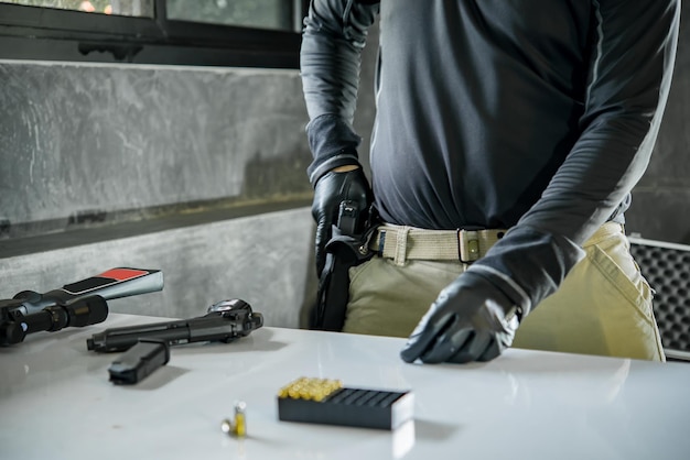 Asian male wearing black leather gloves with gun in handloading bullets to gun