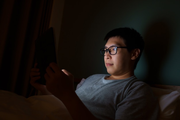 Asian man between the ages of 35 and 40 plays a laptop in his bed. Concept of technology,