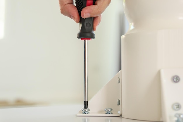 Asian man assembling white table furniture at home