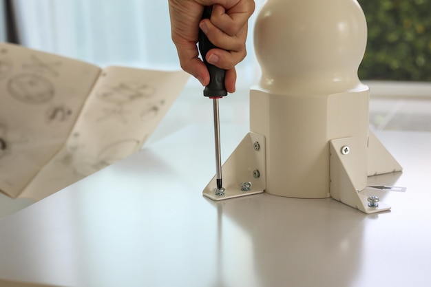 Asian man assembling white table furniture at home