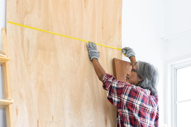 Asian man carpenter working on woodworking in carpentry shop Carpenter working on wood craft at workshop construction material wooden furniture Asian man works in a carpentry shop