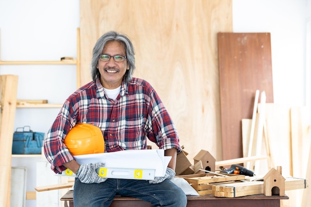 Asian man carpenter working on woodworking in carpentry shop Carpenter working on wood craft at workshop construction material wooden furniture Asian man works in a carpentry shop