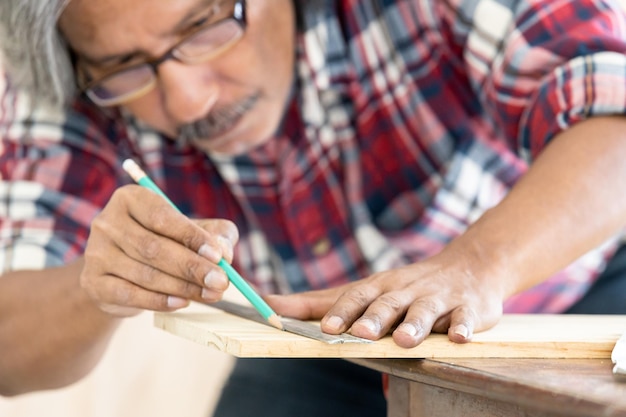 Asian man carpenter working on woodworking in carpentry shop Carpenter working on wood craft at workshop construction material wooden furniture Asian man works in a carpentry shop