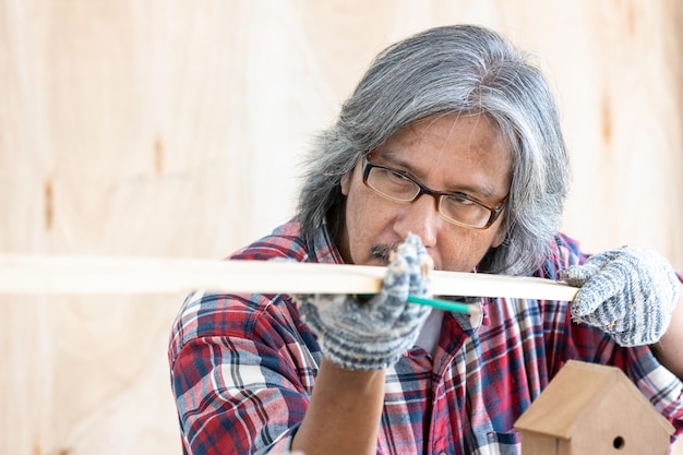 Asian man carpenter working on woodworking in carpentry shop Carpenter working on wood craft at workshop construction material wooden furniture Asian man works in a carpentry shop