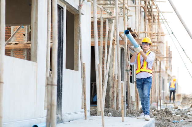 Asian man construction worker holding pipe and working on site.