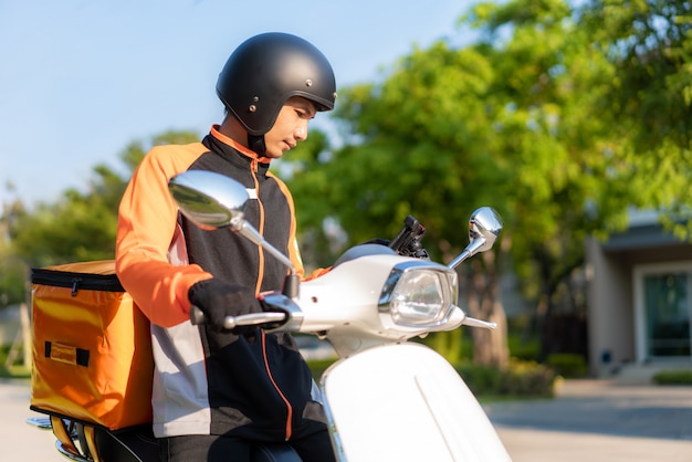 Asian man courier checking customer location in map in smartphone on scooter delivering food