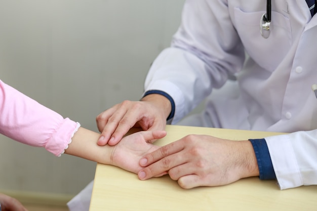 Asian man  doctor examining the patients pulse by hands.