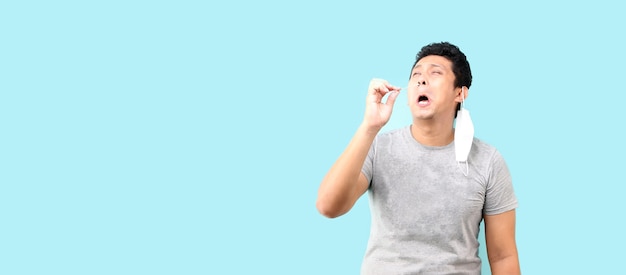 Asian man does a self test for Covid 19 on blue background