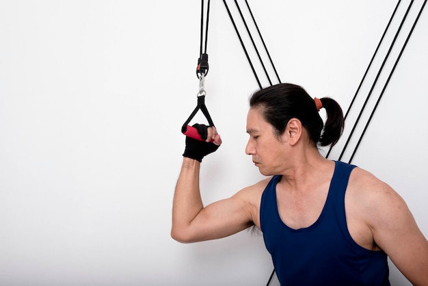 Asian man doing exercise By focusing on tightening the upper arm muscles by puling the rope