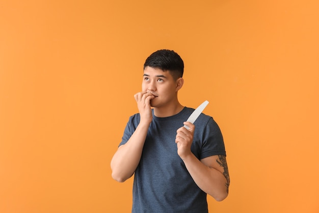 Asian man doing manicure on color surface