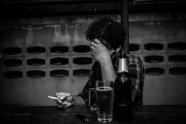 Photo asian man drinking beer and smoking alone at home on night timethailand peoplestress man drunk concept