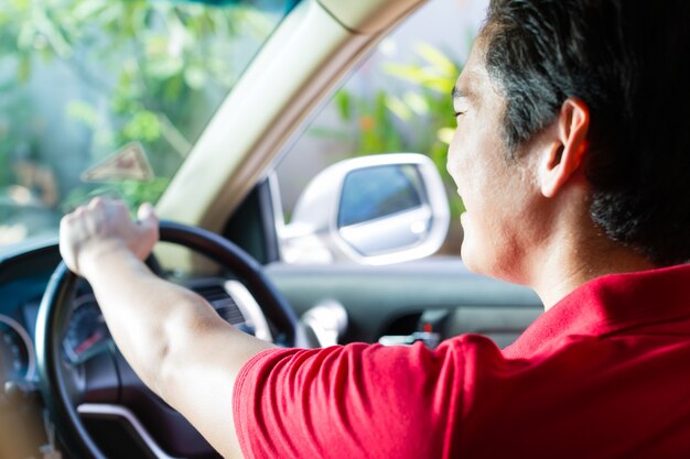 Asian man driving new car