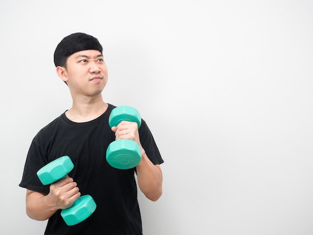 Asian man exercise with dumbbell feeling enjoy and looking at copy space