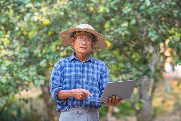 Asian man farmer with smart phone and laptop business and technology concept