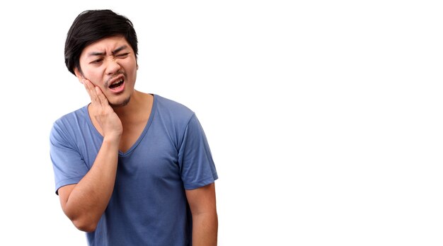 Asian man feeling pain, holding his cheek with hand, suffering from bad tooth ache.