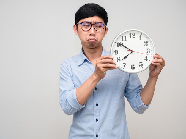 Asian man glasses looking at clock in hand feels bored to working